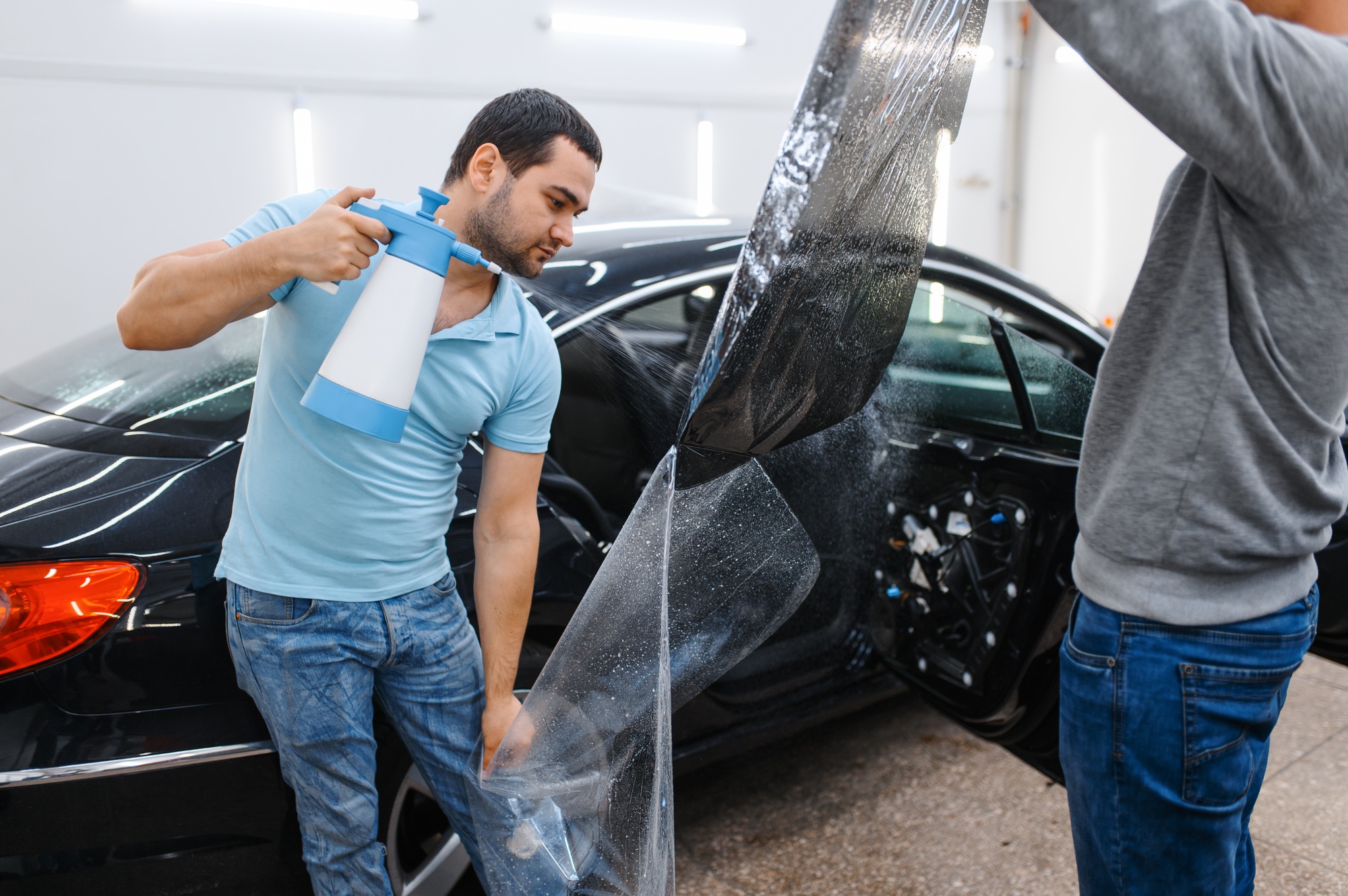 Male worker with spray wetting car tinting