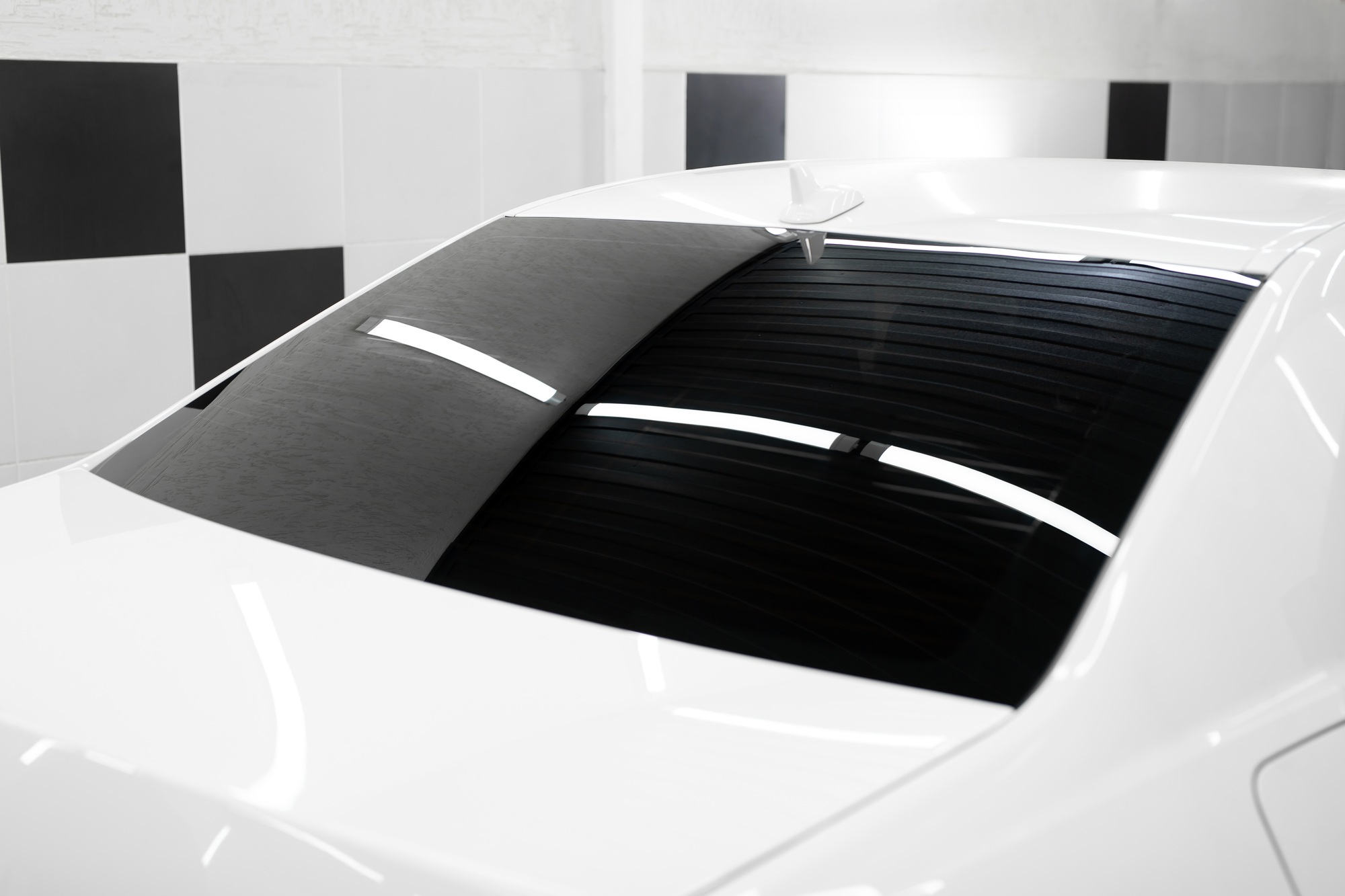 Tinted black car windows reflecting the ceiling and lamps. Detailing studio.